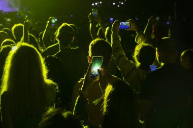 Konserde cep telefonu olan insanlar. Cep telefonlu eller. Bir konserde halk cep telefonuyla fotoğraf çekiyor..