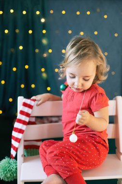 Kırmızı pijamalı çocuk Noel süsleme odası. Kış tatili, yeni yıl arifesi