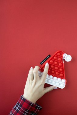Çocuk oyuncağı anti-stresli, kırmızı arka planda Noel Baba şapkası takıyor. - Yeni yıl modeli. Boşluğu kopyala
