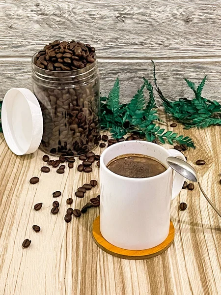 Ahşap arka planda kavrulmuş fasulyeli bir fincan kahve.