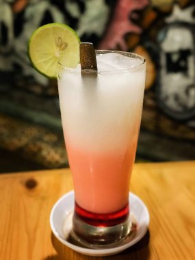 Masada limon olan bir bardak taze kokteylin dikey görüntüsü. yakın plan.