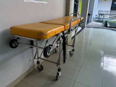 Hastane koridorunda sarı bir sedye.