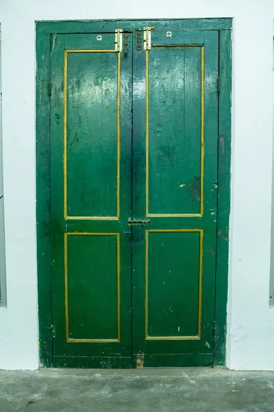 Eski beyaz bina renginde sarı listeli güzel yeşil ahşap kapı.