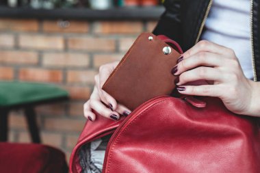 The girl takes out a leather wallet from her bag