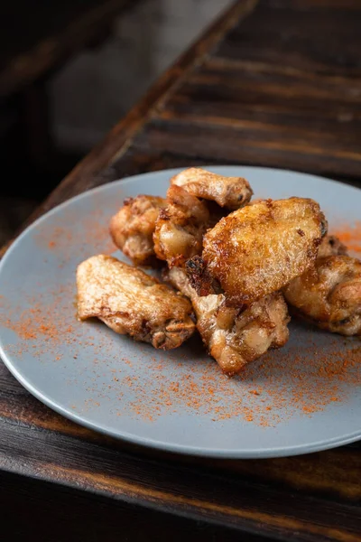Жареные куриные крылышки в тарелке на деревянном столе — стоковое фото