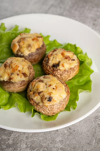 Baked champignons caps with vegetables and cheese in a plate on a gray background Stock Image