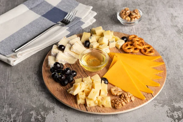 Асорті сир на дерев'яній тарілці на сірому фоні — стокове фото