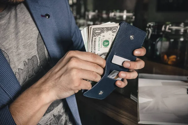 一个男人把钞票从他的皮夹里取出来 图库照片