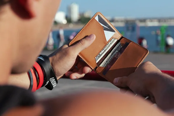 A man holds a leather wallet with dollar bills Stock Picture