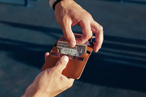 一个男人拿着一个装有美元钞票的皮夹 图库照片