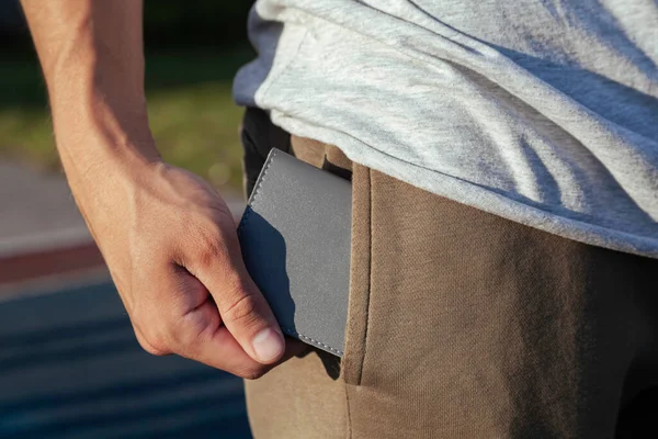 The young man puts a gray leather wallet in his back pocket Stock Image