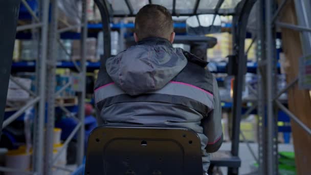 Achteraanzicht vorkheftruckchauffeur rijdt langs rijen in industrieel magazijn met medewerkers aan het praten. Professionele lader operator het besturen van machines in magazijn binnen in slow motion. Live camera. — Stockvideo