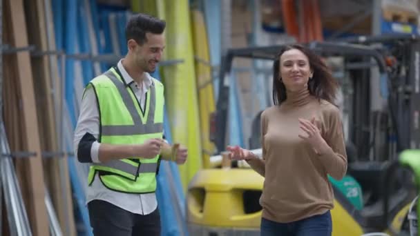倉庫内で踊っている制服姿の明るい中東人男性と白人女性が屋内笑顔でお出迎え。幸せな従業員と貨物代理店の中のショットの肖像画は、記憶に室内で楽しんで. — ストック動画