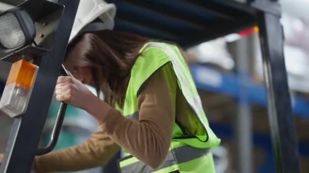 라이브 카메라는 창고에 앉아 있는 자신있는 여성 운전자 자동 로더 기사를 추적 한다. 공장 창고에서 딱딱 한 모자를 쓰고 일하는 직업적 인 여자. — 비디오
