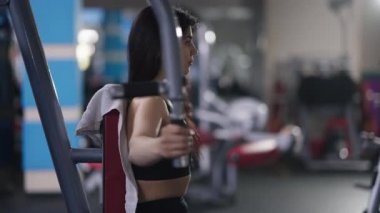 Muhteşem ince Orta Doğulu sporcu kadın göğüs uçuşu makinesinde el eğitimi veriyor. Spor salonunda çalışan kendine güvenen fit bir kadının orta boy görüntüsü. Çaba ve spor konsepti.