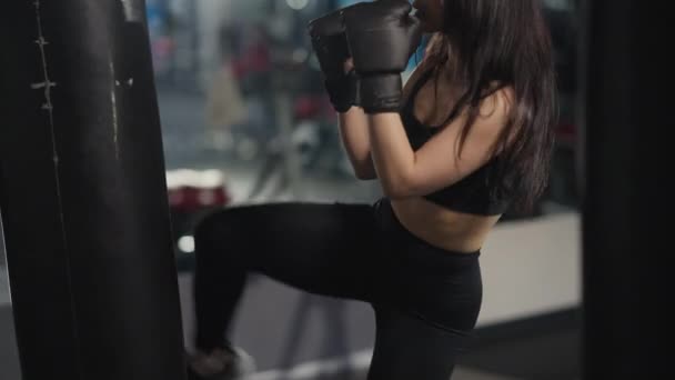 Sac de boxe sportif mince en forme méconnaissable dans la salle de gym avec les jambes et les mains. Endurant confiant motivé entraînement de chasseurs du Moyen-Orient à l'intérieur. Arts martiaux et musculation mixtes. — Video