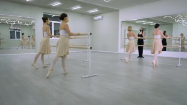Covid-19 maskeli beyaz genç balerinlerin prova yaptığı geniş açılı bale stüdyosu. Koronavirüs salgını karantinasında dans eden kendine güvenen yetenekli kadınlar..