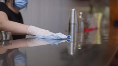 Kafe restoranında kadın el temizleme tezgahı olan bir bar tezgahı. Tanımlanamayan beyaz kadın çalışan yüz maskeli. Coronavirüs salgınında mobilyaları dezenfekte ediyor..