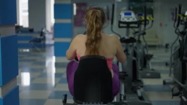 Arka manzara, spor salonunda spor bisikletine binen, motive edici, büyük beden bir kadın. Genç, beyaz, kilolu sporcu kadın, antrenman yapıyor, kilo veriyor. Sağlıklı yaşam tarzı ve motivasyon.
