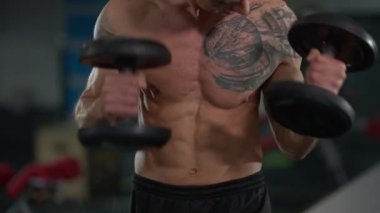 Orta Doğulu erkek vücutçunun kaslı, çıplak gövdesi dambıl kaldırıyor. Tanımlanamayan motivasyon odaklı sporcu spor salonunda ekipmanla çalışıyor..