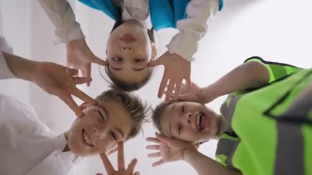 Bottom view cheerful friends siblings grimacing making faces looking at camera. Joyful funny Caucasian teenage boys and girl having fun posing indoors. — Stock Video