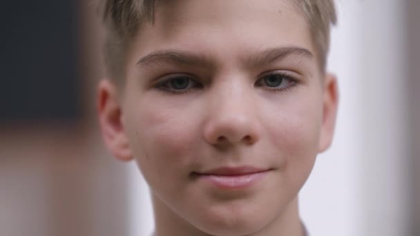 Retrato headshot de sorrir adolescente garotinho caucasiano confiante olhando para câmera. Close-up rosto feliz de encantador adolescente bonito posando dentro de casa. Conceito de confiança e estilo de vida. — Vídeo de Stock