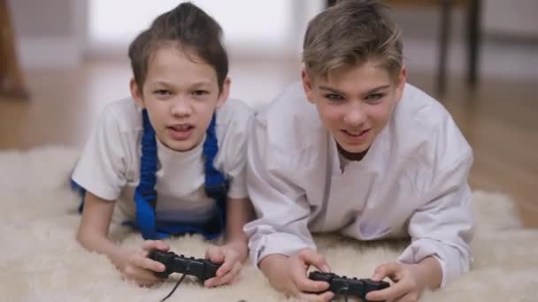 Front view χαρούμενη έφηβους αδελφούς στο γιατρό και οικοδόμος ομοιόμορφη gaming online γελώντας μιλάμε. Πορτρέτο των χαρούμενων ανέμελα θετικά Καυκάσια αγόρια διασκεδάζουν παίζοντας βιντεοπαιχνίδι στο σπίτι σε εσωτερικούς χώρους. — Αρχείο Βίντεο