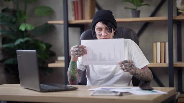Problémás férfi tetovált elemző könnyezik papírmunka gondolkodás otthon irodájában Covid-19 pandémiás karantén. A túlterhelt kaukázusi férfi portréja a projekttervezési stratégia elemzéséről. — Stock videók