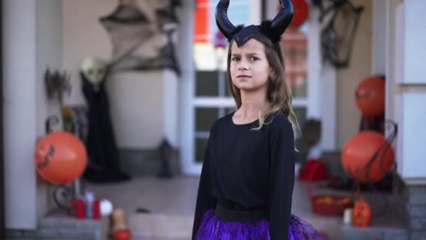 Retrato de chica bonita en disfraz de Halloween de pie al aire libre esperando como niño caminando fuera de casa decorada asustando amigo. Alegres niños caucásicos divirtiéndose en All Hallows Day al aire libre. — Vídeos de Stock