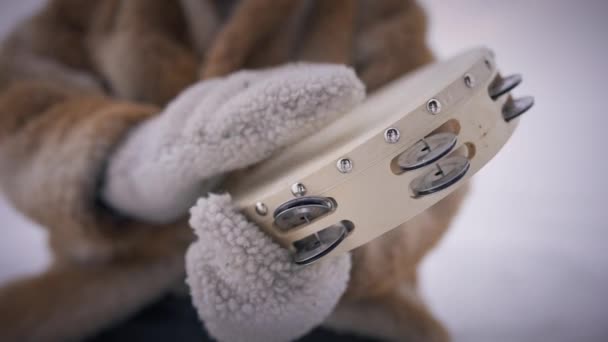 Close-up tambourine in male hands in mittens drumming in slow motion. Unrecognizable old indigenous man playing folk music on percussion instrument outdoors on icy snowy winter day. — Stock Video