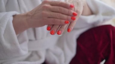 Yakın plan, olgun bir kadın avuç içi nemlendiricisine sürtünüyor. Tanımlanamayan beyaz bir kadın evde güzellikle ilgileniyor. Sabah rutini konsepti.