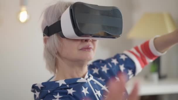Absorberet moden kvinde i VR headset bevægelige hænder nyder augmented reality hjemme i stuen. Close-up glad afslappet kaukasiske dame spiller videospil indendørs. Levende kamera. – Stock-video