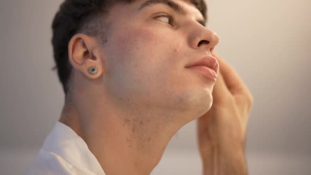 Vista laterale LGBT uomo massaggiare il viso con gua sha a casa al mattino. Close-up fiducioso non binario queer persona al chiuso facendo procedura di cura della pelle. Rallentatore. — Video Stock