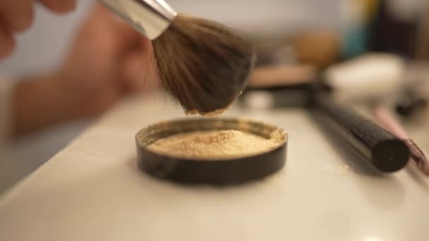 Frasco de pó facial close-up na mesa com escova dentro de casa. Processo de maquiagem em câmera lenta dentro de casa. — Vídeo de Stock