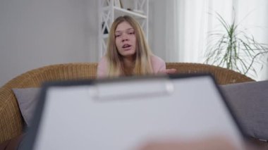 Önünde bulanık kadın el yazısıyla konuşan histerik bir kadının portresi. Kafkasyalı genç hasta danışman psikolog içerde kanepede oturuyor..