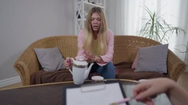 Genç bin yıllık hasta psikoloji ofisinde oturup fincana çay doldurarak psikologla konuşuyor. Elinde kalem ve önünde el kol işareti olan bir kadın. Stresli beyaz kadın randevuda..