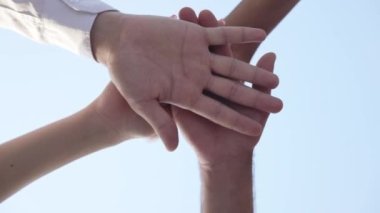 Arka planda açık mavi gökyüzü olan çok ırklı gençlerden oluşan yakın çekim yığını. Yavaş çekimde el ele tutuşan kendine güvenen erkek ve kadınların ayrılması. Birlik ve dostluk kavramı.