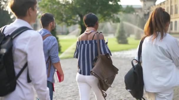 Live camera segue gruppo di studenti multietnici a piedi al mattino al campus universitario al rallentatore. Fiduciosi caucasici mediorientali e afroamericani uomini e donne che passeggiano all'aperto. — Video Stock