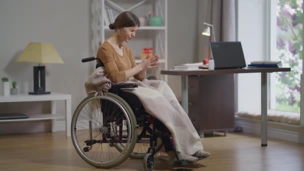 Overweldigde jonge gehandicapte vrouw in rolstoel sluitend gezicht huilend alleen thuis. Breed portret van een depressieve blanke vrouw die haar hoofd in de hand houdt. Hopeloosheid en frustratie concept. — Stockvideo