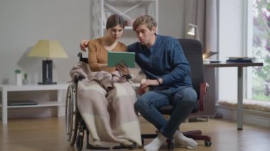 Ön manzara mutlu çift yavaş çekimde el kol hareketi yaparak evde seviniyor. Kafkasyalı engelli kadın ve oturma odasında neşeli bir adam. İlişki ve tıbbi konsept.