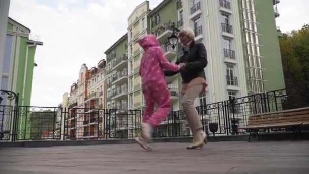 Amplio tiro alegre abuela despreocupada y nieta de la mano bailando en la calle de la ciudad al aire libre. Feliz caucásico senior mujer y pequeño niño disfrutando de ocio divertirse al aire libre. — Vídeo de stock