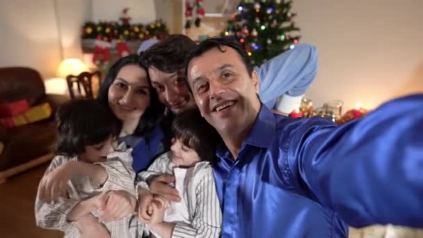 Selfie POV gelukkig Midden-Oosten man neemt foto met familie binnen op kerstavond. Portret van een lachende man genietend van nieuwjaarsviering met blanke vrouw tiener en tweelingbroers. — Stockvideo