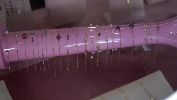 Élégants bracelets dorés en porte-bijoux rose à l'intérieur. Bijoux chères et brillantes vendus en magasin. Marketing et concept de luxe. Mouvement lent. — Video