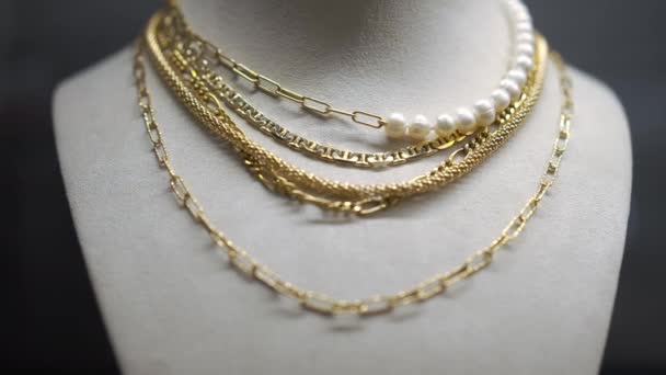 Guldhalsband kedja med vita pärlor närbild i ljus. Lyxig dyr vacker accessoar hängande på hållare i smycken butik. Långsamma rörelser. — Stockvideo