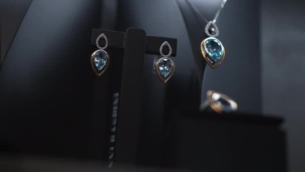 Pendientes con anillo de gemas azules y cadena colgando en el soporte en joyería. Joyas preciosas en escaparate en el interior primer plano. Concepto de lujo. — Vídeos de Stock