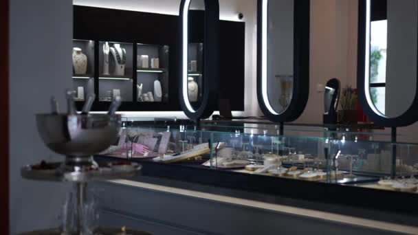 Magazin de bijuterii cu oglinzi și accesorii fine înalte în interior, fără oameni. Bijuterii scumpe de lux pe rafturi sub sticlă în magazinul modern. Slow motion. — Videoclip de stoc