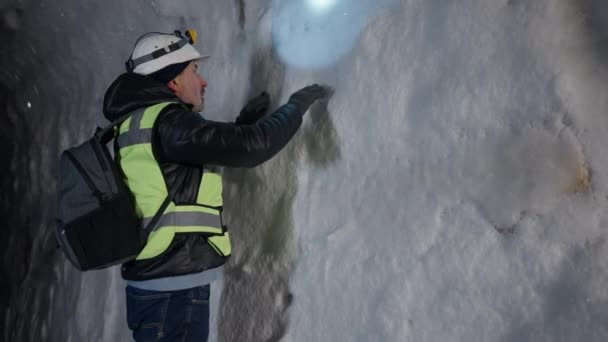 Sebevědomý muž zkoumá ledovou jeskyni se sněhem dotýkajícím se stěn. Portrét kavkazského aktivního cestovatele, který zkoumá sněhovou čepici venku. Koncept přírody a cestovního ruchu. — Stock video