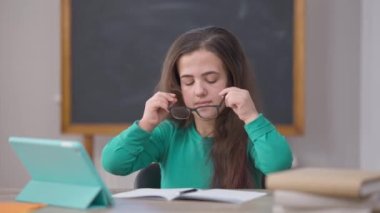 Dahi, konsantre olmuş beyaz kadın portresi. Gözlük takıyor. Kalemle yazı yazıyor. Zeki, kendine güveni olan küçük insan içeride çalışıyor..