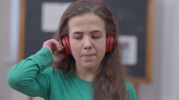Großaufnahme brünette weibliche kleine Person mit Kopfhörer, die Musik einschaltet, die drinnen tanzt. Selbstbewusste junge positive Frau aus dem Kaukasus, die Spaß am Hobby hat. Lebensstil und Gene. — Stockvideo