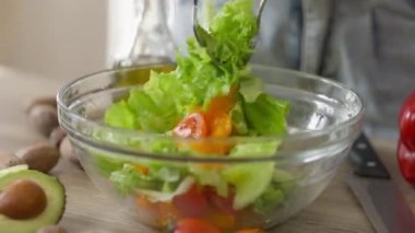 Kapalı mekanda sağlıklı vejetaryen salatasını karıştıran kadın elleri. Tanımlanamayan beyaz kadın sabahları evde diyet sebze hazırlıyor. Sağlıklı yaşam tarzı kavramı.